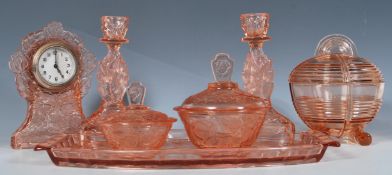 An early 20th Century Art Deco pink pressed glass dressing table set having impressed rose