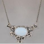 A substantial silver pendant necklace set with a central moonstone cabochon in a decorative floral