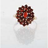 An English hallmarked 9ct yellow gold cluster ring. The ring prong set with red stones on a