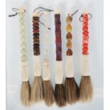 A group of five 20th Century African dust / swat brushes having precious stone beaded handles with