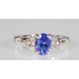 A stamped 14ct white gold ring set with an oval cut blue stone flanked by six round cut white