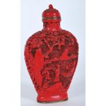 A Chinese 20th Century red cinnabar snuff bottle carved with landscape scenes having carved