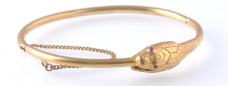 AN ANTIQUE OUROBOROS GOLD AND RUBY SNAKE BANGLE