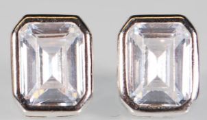 A pair of silver stud earrings set with emerald cu