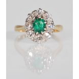 An 18ct gold, platinum diamond and emerald ring. The central emeral of oval cut within a halo of