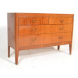 A 1970's teak wood Danish influence low chest of drawers being raised on tapered legs with a bank of