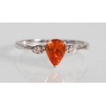 A stamped 9ct white gold ring set with a teardrop cut orange stone flanked by two round cut white