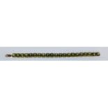 A stamped 375 9ct gold tennis bracelet set with cushion cut green stones. Weight 20.9g. Measures 7