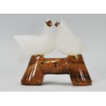 A 20th Century carved white stone figurine ornament in the form of two doves, perched on a brown