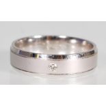 An English hallmarked 9ct white gold band ring having a central brushed section set with a round cut