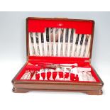 A silver plated cutlery canteen set within a wooden case, each piece having scrolled design
