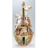 A 20th Century Italian ceramic lamp base in the form of a cello with applied florals and cherubs.