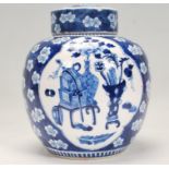 A Chinese blue and white lidded ginger jar being hand painted with blossoms having cartouche