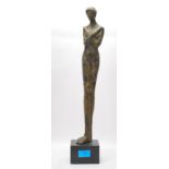 A contemporary bronze figurine in the form of a elongated nude male figure with crossed arms
