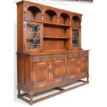 A Jaycee medium oak linen fold drawer dresser with lead glazed display cupboard flanked by carved