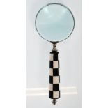 A desktop magnifying glass having a black and white checkerboard handle of tapering form. Measures