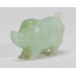 A Chinese jade carved figurine in the form of a stylised pig raised on all four legs looking upward.