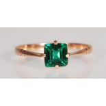 A stamped 9ct gold ring set with a square cut green stone with tapering faceted shoulders. Weight