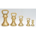 A selection of 20th Century graduating brass bell weights having carrying handles atop, with the