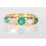 A hallmarked 18ct gold ladies ring set with three round cut emeralds and two round cut diamonds.