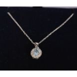 A ladies 18ct white gold pendant necklace set with an oval cut blue topaz surrounded by a halo of