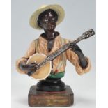 A 19th Century Austrian cold painted ceramic figurine depicting a black man playing the banjo