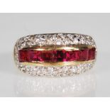 A 9ct gold ruby and white stone Art Deco style dress ring. The domed ring having channel set