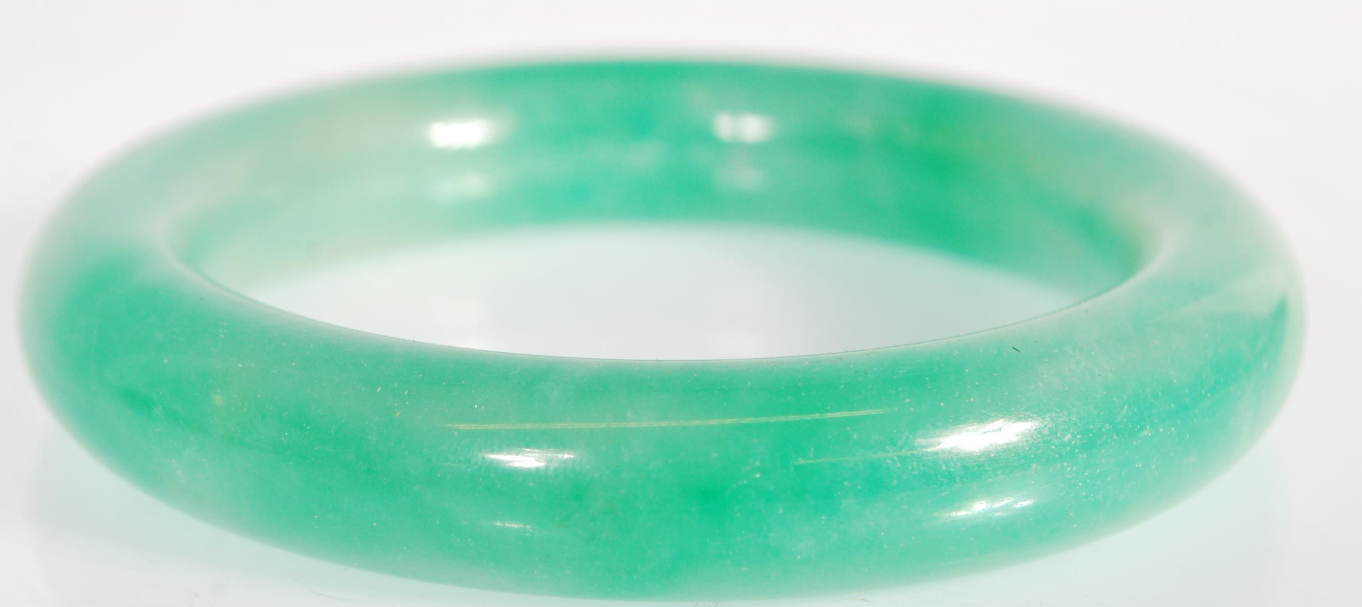 A Chinese green jade bangle of typical round form. Interior diameter 5.9g. Measures 99.4g. - Image 3 of 3