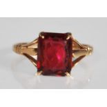 A marked 9ct yellow gold ring having a square cut red stone set to a decorative pierced mount with