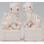 A pair of Chinese blanc de chine fu / temple dog figurines raised on rectangular plinth bases,
