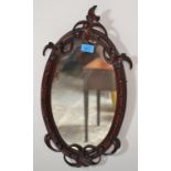 A 20th Century Victorian style carved mahogany wall mirror of oval form. The frame having carved