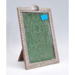 A silver hallmarked picture frame with relief decorated frame having plain cartouche panel with