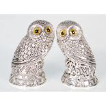 A pair of silver plated condiments in the form of a owls sitting on naturalistic bases with yellow
