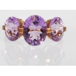 A 9ct gold hallmarked amethyst trilogy dress ring, large central oval cut stone flanked by two