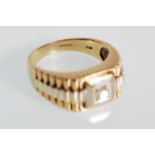 A stamped 375 9ct gold ring of two tone stepped design set with a round cut diamond to the head.