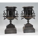 A pair of 19th Century neo-classical slate mantel piece urns raised on stepped square bases having