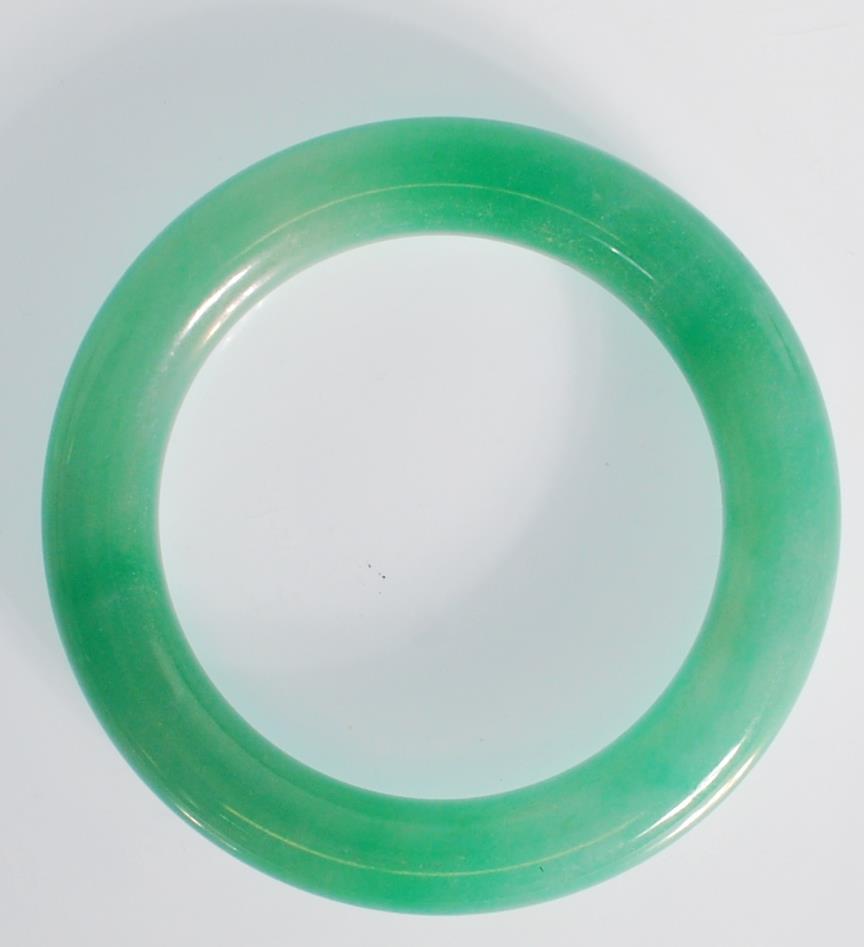 A Chinese green jade bangle of typical round form. Interior diameter 5.9g. Measures 99.4g. - Image 2 of 3