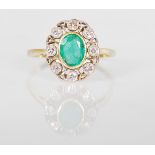 A hallmarked 18ct gold ladies dress ring set with an oval cut emerald surrounded by nine round cut