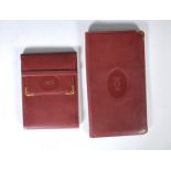 Les Must De Cartier Paris- Two unused burgundy leather wallets / purses by Cartier. Each wallet