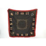 An early 20th Century French embroidered felt table cloth having a black ground with red boarder