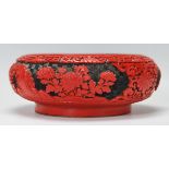 A 20th Century Chinese cinnabar dish of round form having carved peony panels raised on a round foot