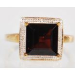 A 9ct gold Princess cut garnet and diamond dress ring, stamped 375 large central garnet stone
