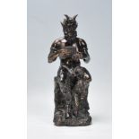 A cast faux bronze classical figurine sculptural ornament in the from of a satyr holding a set of