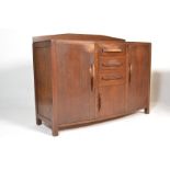 A 1920's oak Arts & Crafts Cotswold School manner sideboard having end cupboards with central bank