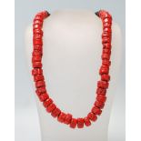 A 20th Century beaded coral necklace having 47 large cylindrical beads set onto a black strung