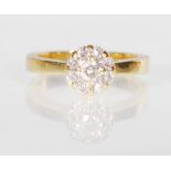 A stamped 18ct gold ring set with a cluster of diamonds, consisting of a central round cut