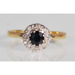 A hallmarked 18ct yellow gold ring set with a central round faceted cut sapphire with a halo of