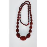 An early 20th Century cherry bakelite necklace consisting of graduating oval beads. Measures 36