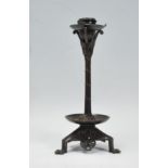 A late 19th / early 20th Century Arts and Crafts case bronzed candlestick raised on a tripod base