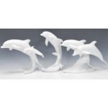 A group of three Kaiser porcelain figures in the form of dolphins raised on moulded wave bases. Each